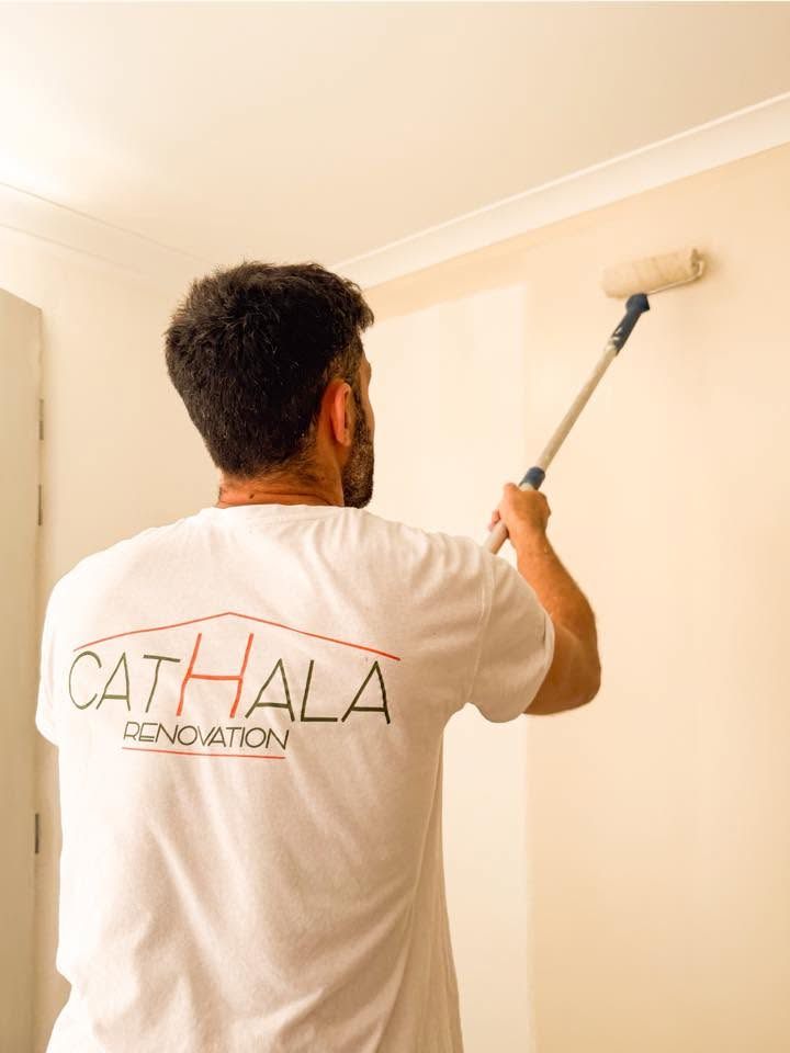 Emmanuel Cathala en train de peindre un mur au rouleau sur perche, en t-shirt Cathala Rénovation
