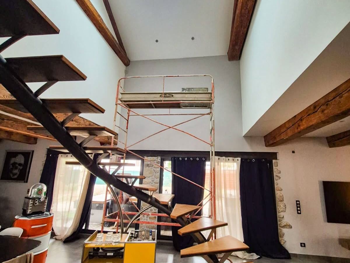 Pièce à vivre d'un mas en cours de chantier : échafaudage roulant sous les poutres et mobilier protégé