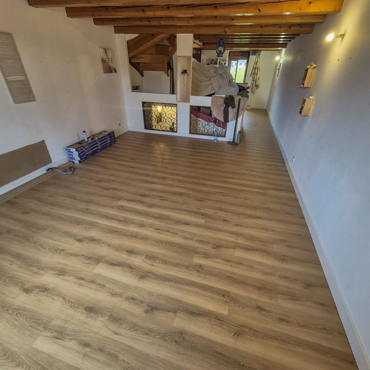 Le même séjour avec son parquet chêne posé sur toute la longueur, sous les poutres apparentes