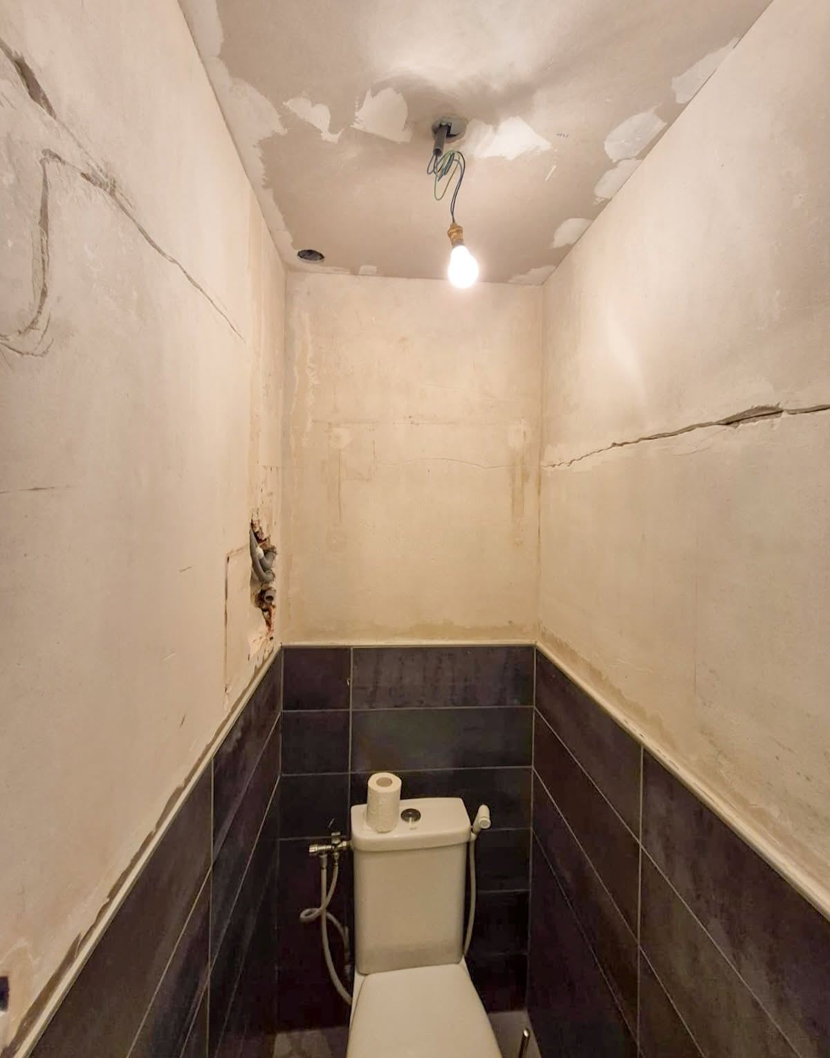 WC avant travaux : faïence brune en demi-hauteur, murs fissurés et plafond écaillé