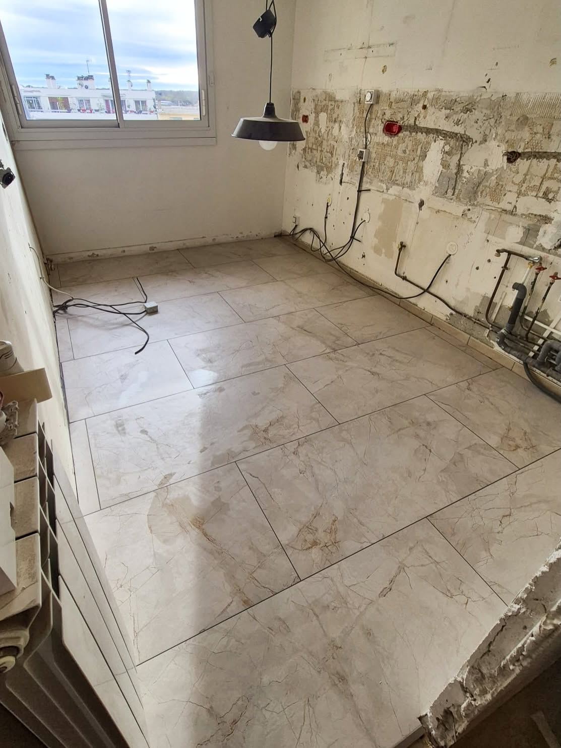 Pièce mise à nu avant travaux : murs piqués, saignées électriques apparentes et ancien carrelage au sol