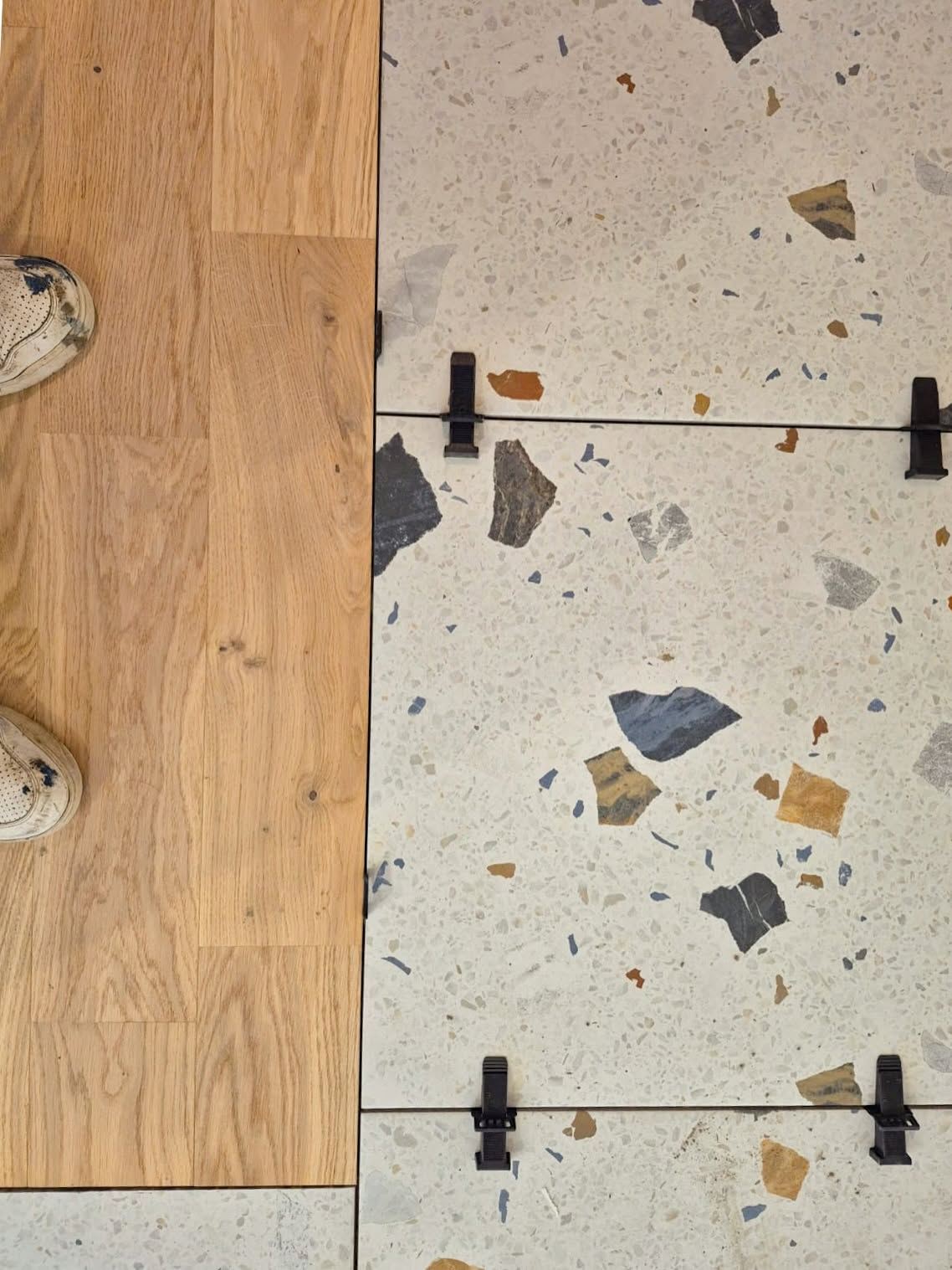 Jonction entre un carrelage effet terrazzo et un parquet, dalles maintenues par des croisillons autonivelants